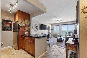 A spacious living area with a kitchen, dining area, and a balcony with a view.