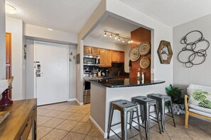 A modern kitchen with stainless steel appliances, a central island with stools, and decorative wall art.
