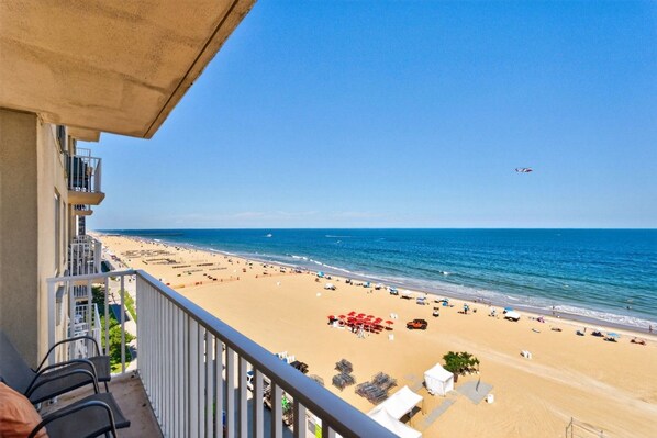 A balcony overlooking a beach with a clear view of the ocean and beachgoers.