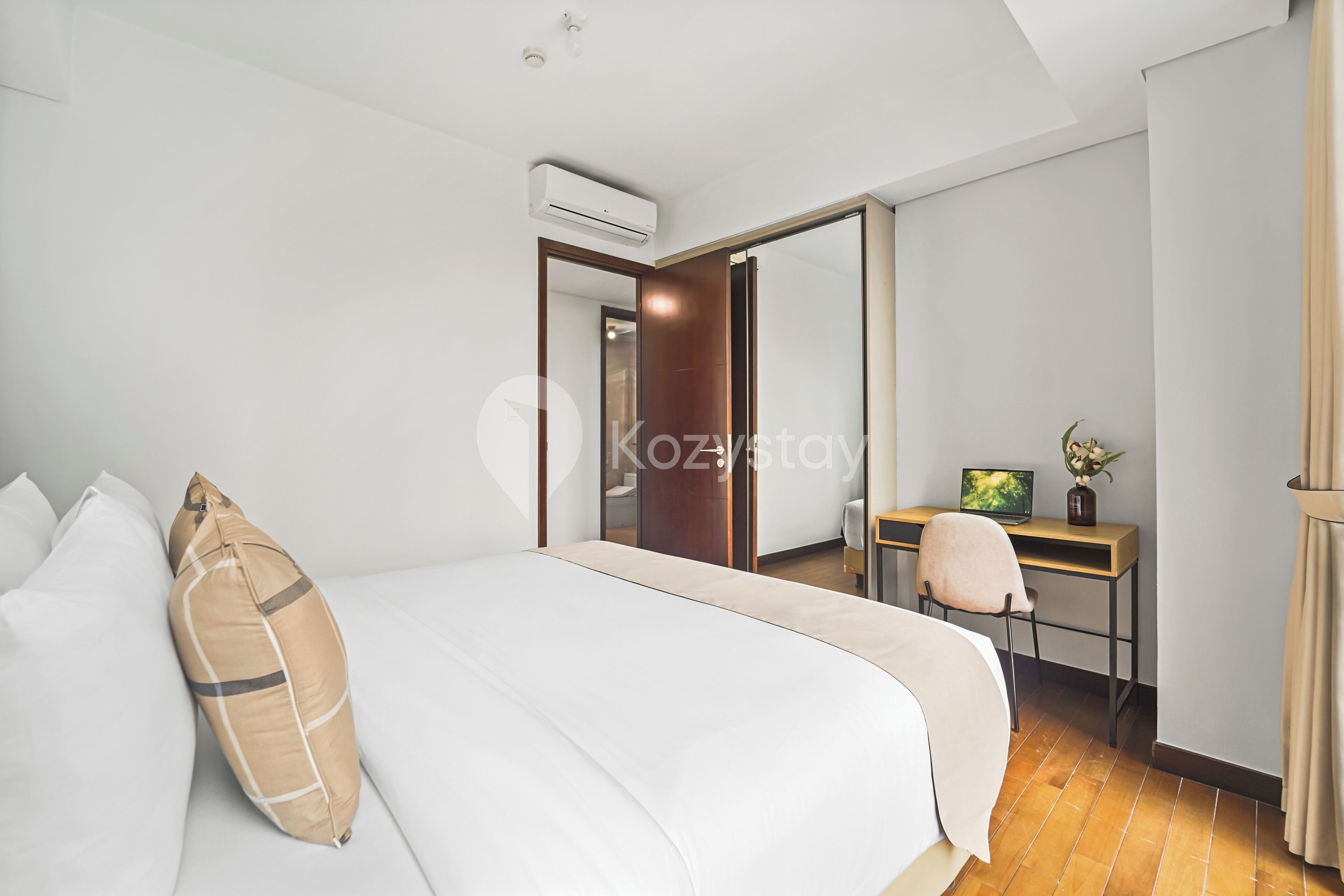 Una habitación de hotel moderna con una cama grande, un escritorio con computadora y un espejo.