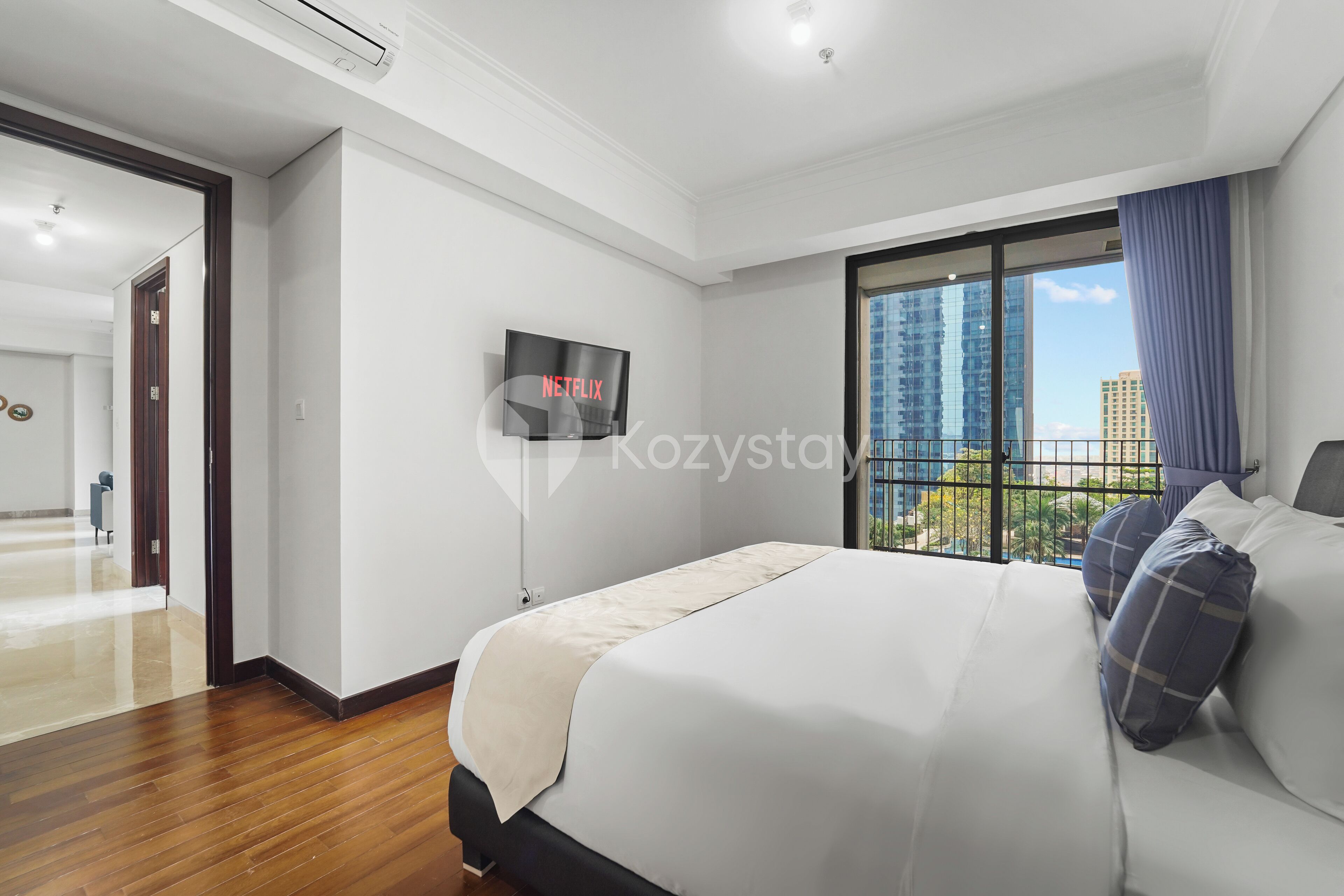 Una habitación de hotel moderna con una cama grande, televisión y vistas a edificios altos.