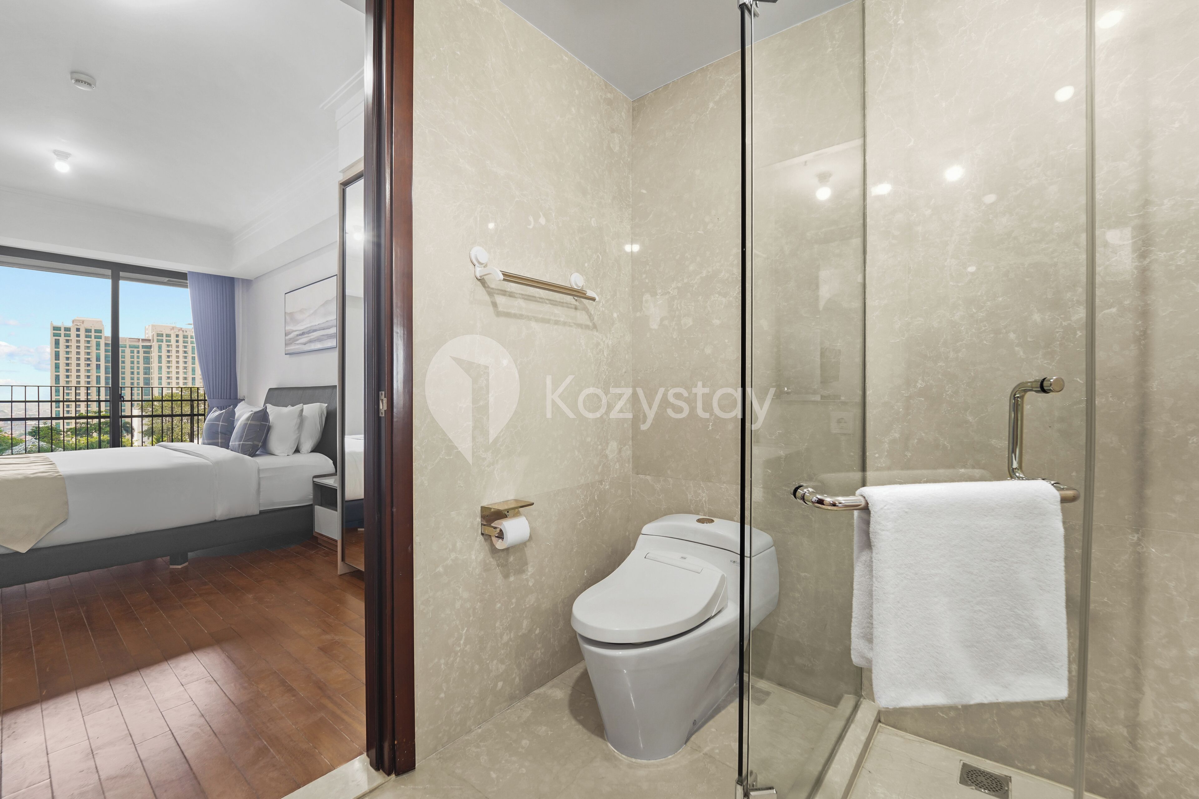 Une salle de bain moderne avec une douche à parois de verre, des toilettes et un porte-serviettes.