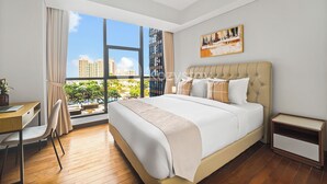 Habitación de hotel moderna con una cama grande, un escritorio y una silla. Se ve una ventana con vistas a edificios y áreas verdes.