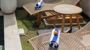 A rooftop terrace with two wicker lounge chairs, a small round table, a potted plant, and a pool. - Oceanview Escape 1BR Villa Bingin, Uluwatu (Bali)