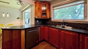 Une cuisine moderne avec des meubles en bois, un plan de travail noir et une grande fenêtre.