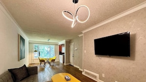 Un salon moderne avec un canapé, une table basse et un téléviseur à écran plat fixé au mur.