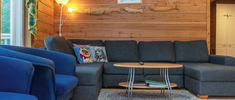 Ein gemütliches Wohnzimmer mit einer Eckcouch, einem kleinen runden Tisch und einer Lampe.
