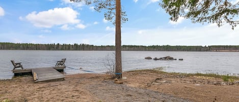 Un cadre idyllique au bord d’un lac, avec un quai, deux chaises et un arbre.