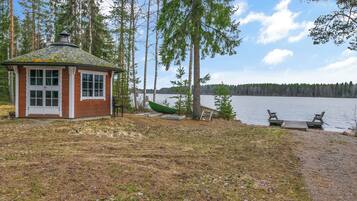 A cabin with a small deck and a dock extending into a lake, surrounded by trees.