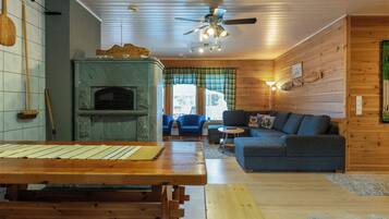 L’intérieur chaleureux d’un chalet avec une cheminée en pierre, des meubles en bois et une vue sur la ville grâce à de grandes fenêtres.