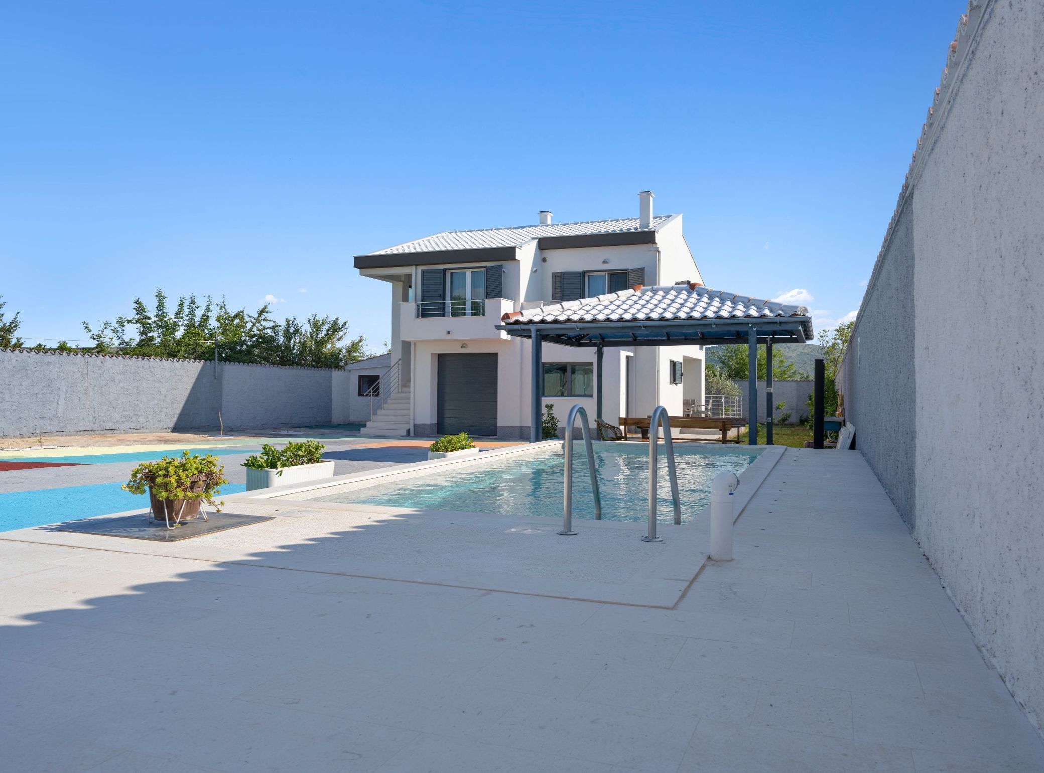 A modern two-story house with a swimming pool, a covered patio, and a garden.