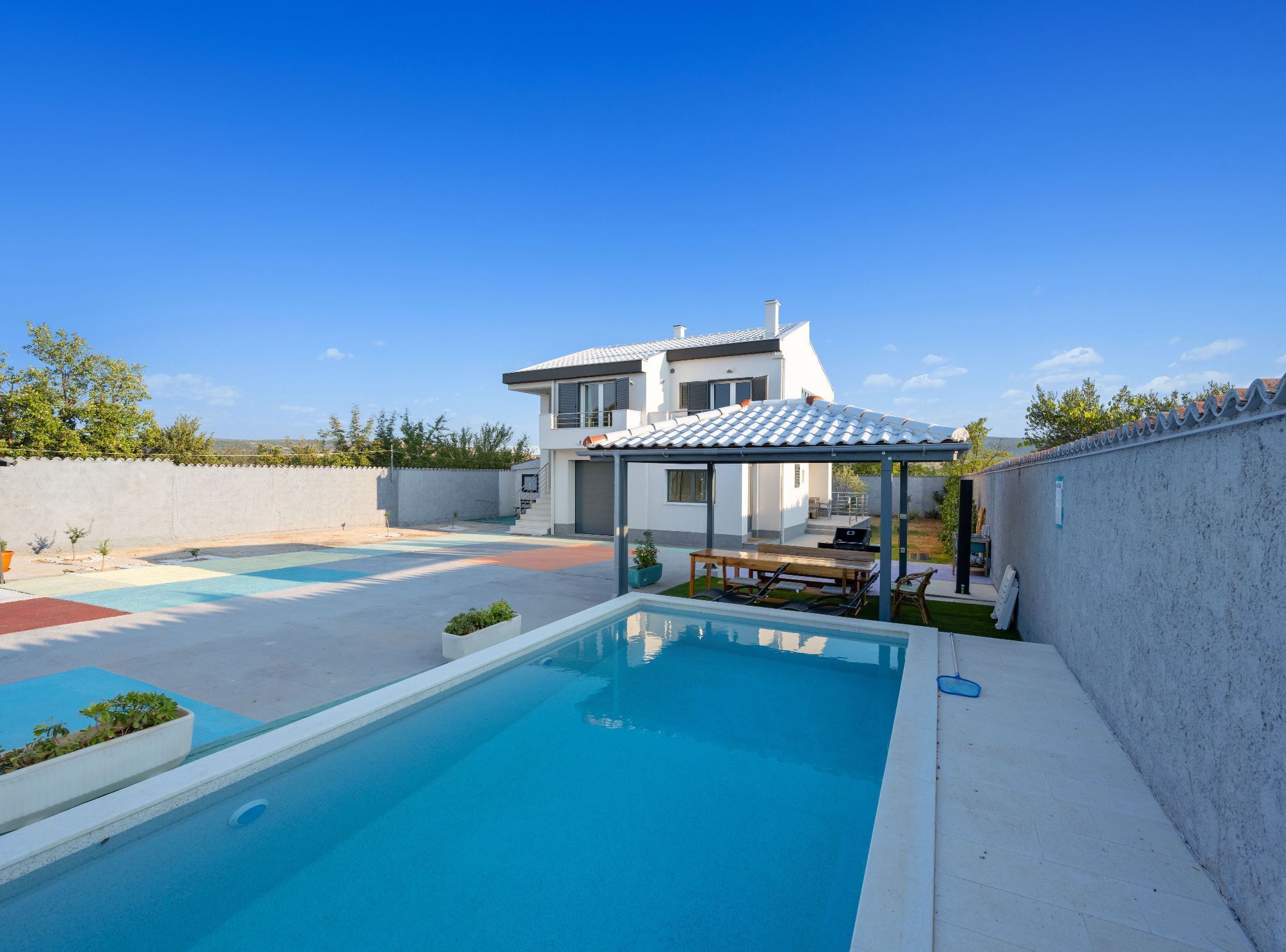 Une maison moderne dotée d’une piscine, d’un patio couvert et offrant une vue sur les environs.
