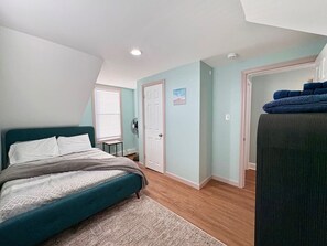 A bedroom with a bed, a door, a fan, and a window.