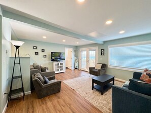 A living room with a sofa, armchairs, a coffee table, and a TV.