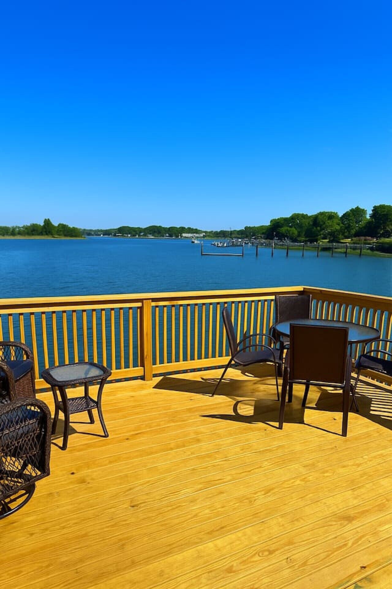 Een houten terras met buitenmeubilair met uitzicht op een wateroppervlak.