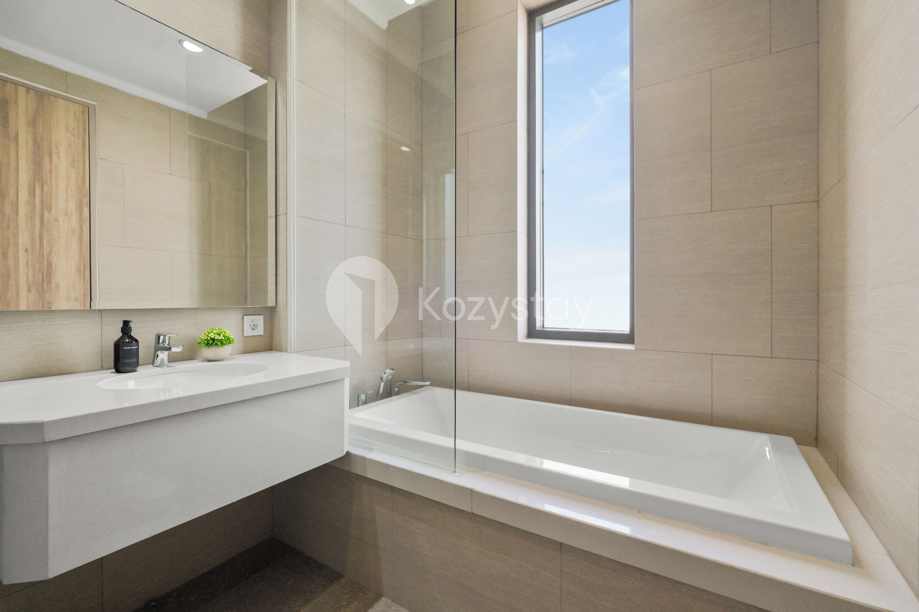Un bagno moderno con una vasca da bagno ampia, un mobile vanità con uno specchio e una piccola pianta in vaso.