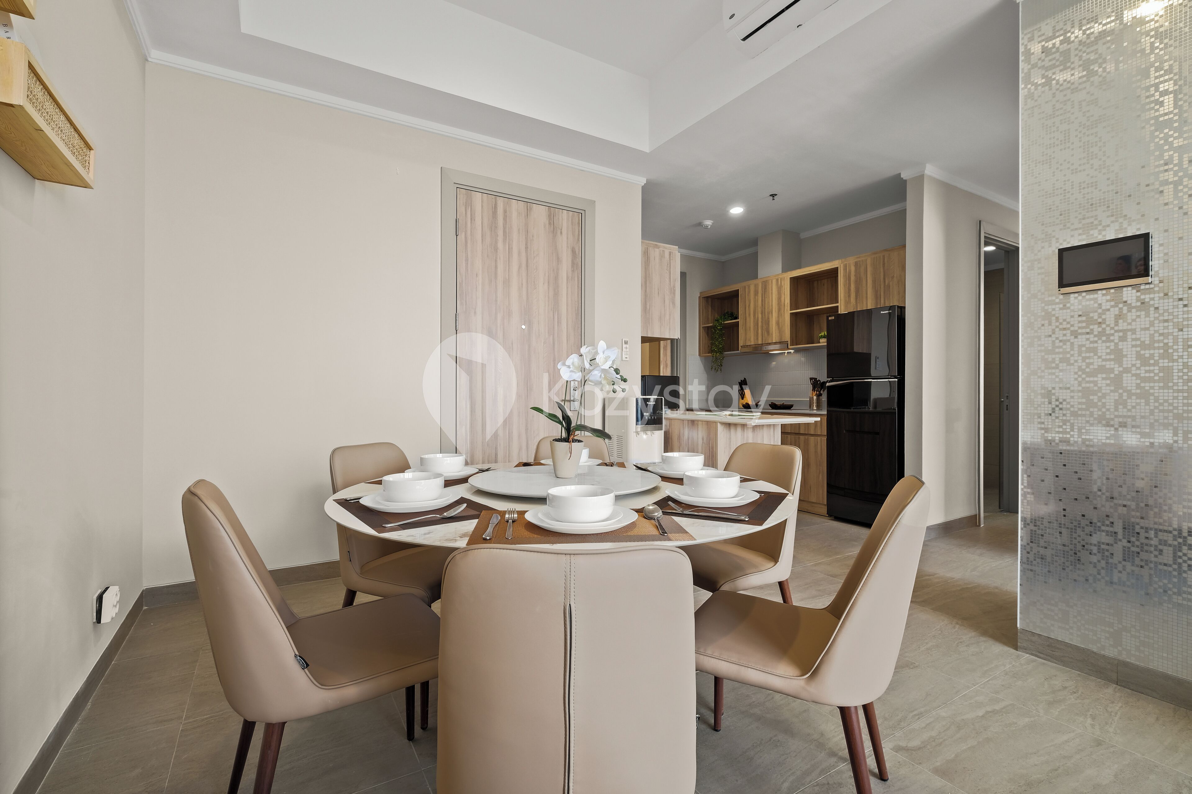 A modern dining area with a round table set for four, surrounded by beige chairs.