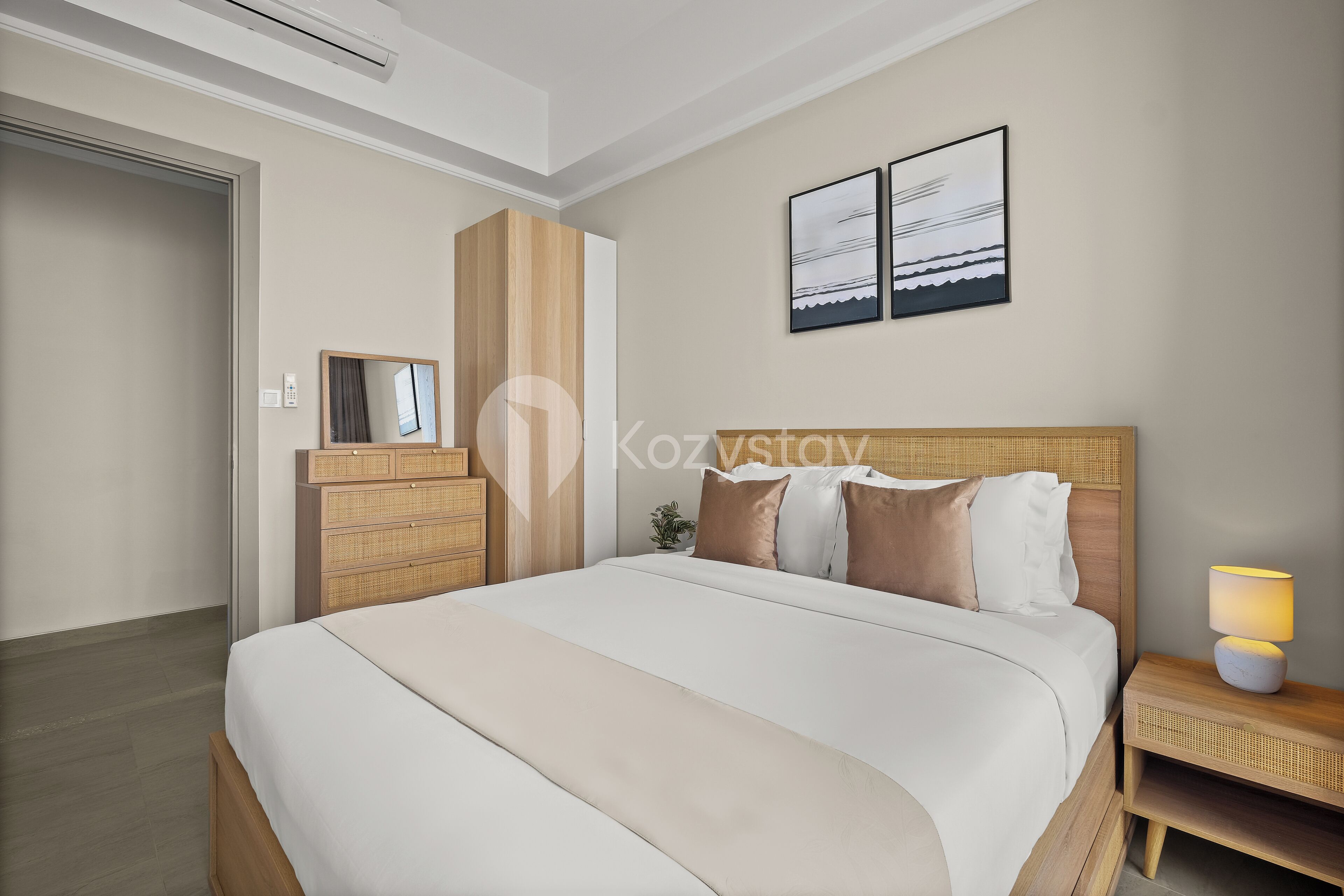 Camera d'albergo con un letto grande, un comodino con una lampada, uno specchio fissato alla parete e due quadri appesi.