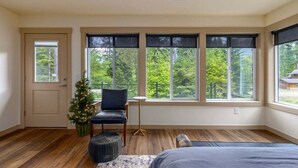 Een slaapkamer met een groot raam, een kerstboom, een stoel en een bed.