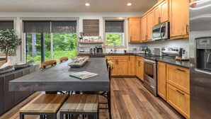 Een moderne keuken met houten kastjes, roestvrijstalen apparatuur en een groot eiland met zitplaatsen.