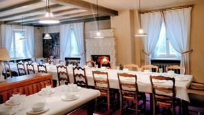 Comedor con mesas dispuestas para el servicio, chimenea y lámparas colgantes.