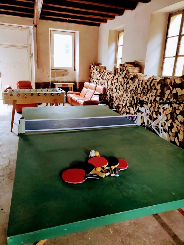 Ett rum med ett fotbollsspel, ett bordtennisbord, en soffa och ett fönster.
