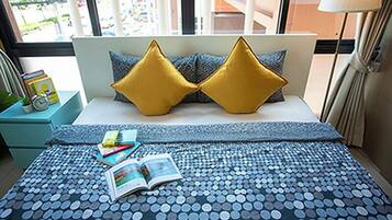 A neatly made bed with a blue and white polka dot bedspread, two gold pillows, and a book on the bed.