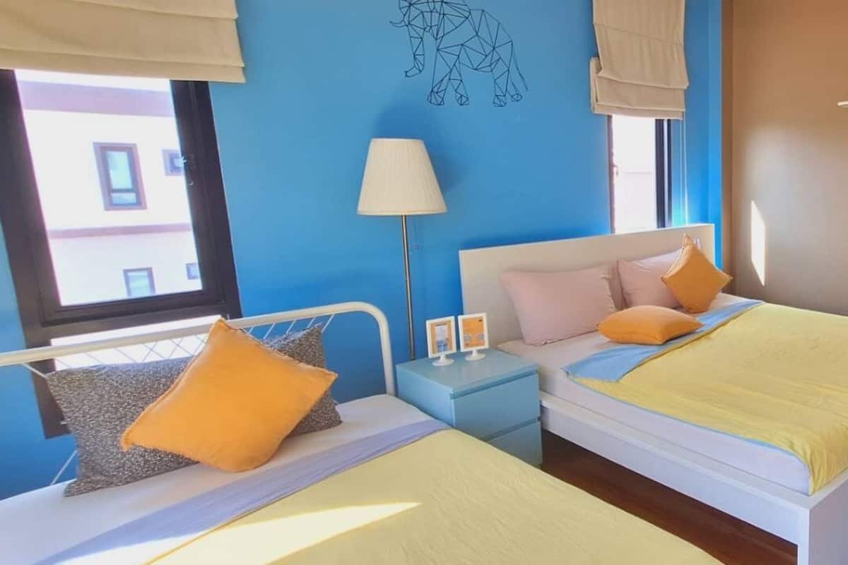 A bedroom with two beds, a nightstand, a lamp, and a wall art piece.