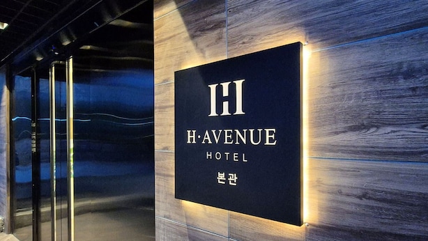 Letrero del Hotel H. Avenue con diseño moderno y letras iluminadas.