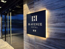 Letrero del Hotel H. Avenue con diseño moderno y letras iluminadas.