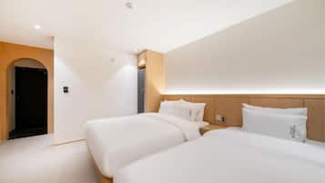 Una habitación de hotel con dos camas, cabecero de madera, un escritorio pequeño y una puerta.