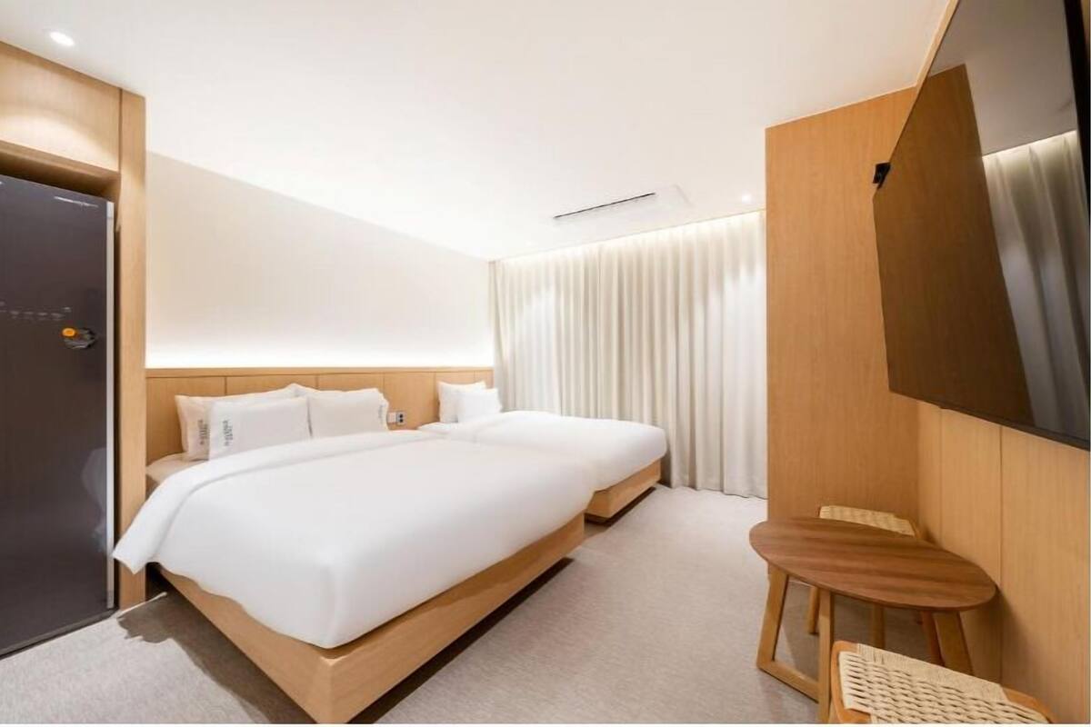 A modern hotel room with a large bed, a small wooden table, and a TV mounted on the wall.