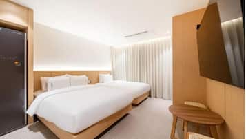 A modern hotel room with a large bed, a small wooden table, and a TV mounted on the wall.