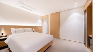 A modern hotel room with a large bed, wooden headboard, and a built-in wardrobe.