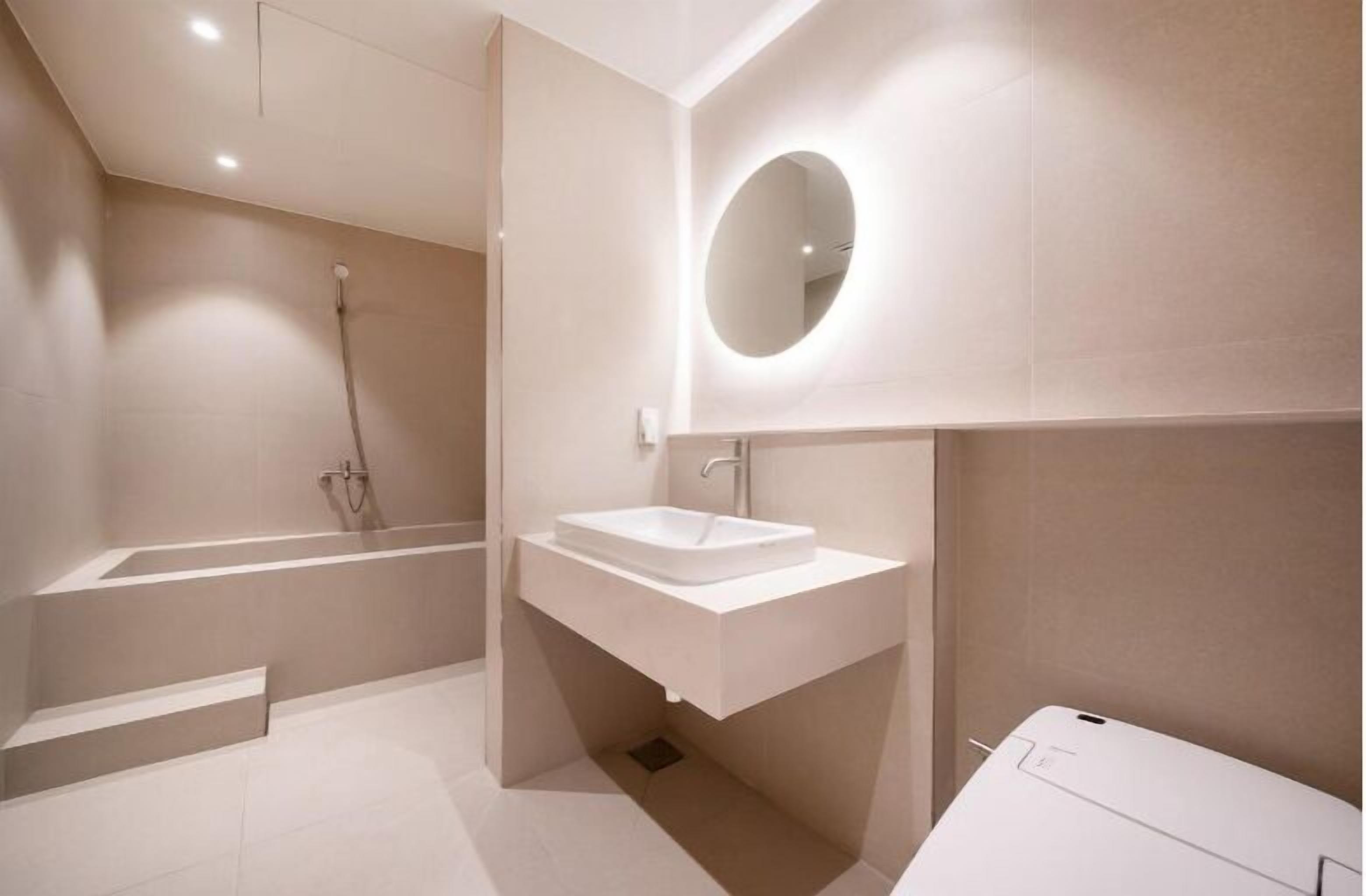 Une salle de bain moderne avec une baignoire sur pieds, un lavabo blanc et un grand miroir.