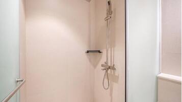 A small, enclosed shower area with a handheld showerhead and a handheld faucet.