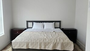 Een slaapkamer met een bed, plafondventilator en houten vloer.