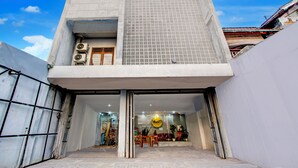 A modern building with a large entrance, air conditioning units, and a visible interior with furniture and plants. - Hotel O Tegal near near Pacific Mall Tegal formerly Hugo Suites Family (Tegal)