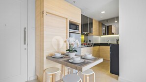Una cocina moderna con una isla de madera, taburetes blancos y una mesa de comedor preparada para cuatro.