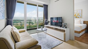 Una habitación de hotel moderna con un ventanal grande, un sofá, un televisor y una cama.