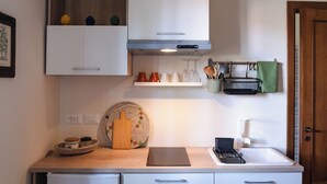 A compact kitchen with white cabinets, a stainless steel range hood, and a small countertop.