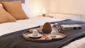 A neatly arranged breakfast tray with cups, saucers, and a book on a bed.