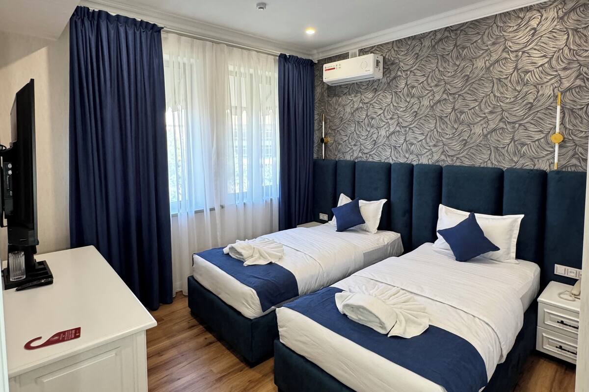 Una habitación de hotel con dos camas, un escritorio y una televisión.