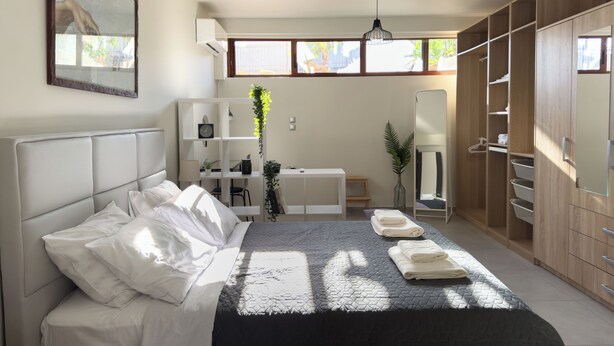 Un dormitorio moderno con cama, mesitas de noche, escritorio, espejo y armario.