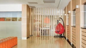 Um interior moderno com uma mesa de recepção, uma cadeira suspensa vermelha e uma parede estampada.