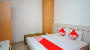 Una habitación de hotel con cama, armario de madera, escritorio y silla.