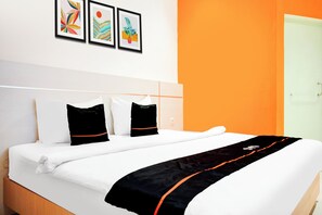 A hotel room with a bed, white bedding, two black pillows, and a black and orange throw. There are three framed artworks on the wall. - Townhouse Oak Palembang near Palembang Golf Club formerly KR Hotel (Palembang)