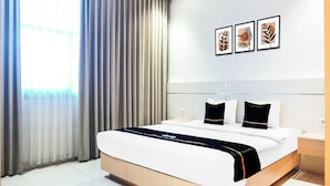 Quarto de hotel com uma cama grande, uma mesa de cabeceira e uma tomada na parede.