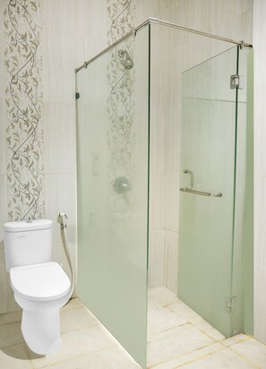 A bathroom with a glass-enclosed shower, a toilet, and patterned wall tiles. - Townhouse Oak Palembang near Palembang Golf Club formerly KR Hotel (Palembang)