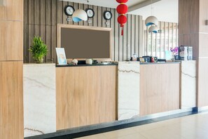 A reception desk with a flat-screen TV, clocks, and a potted plant. - Townhouse Oak Palembang near Palembang Golf Club formerly KR Hotel (Palembang)